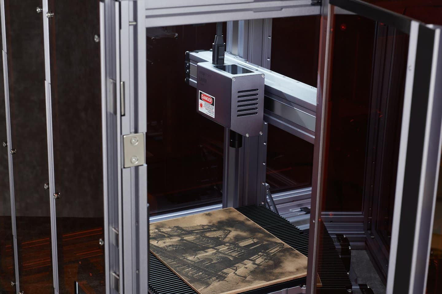Macchina per incisione laser con disegno intricato su legno.
