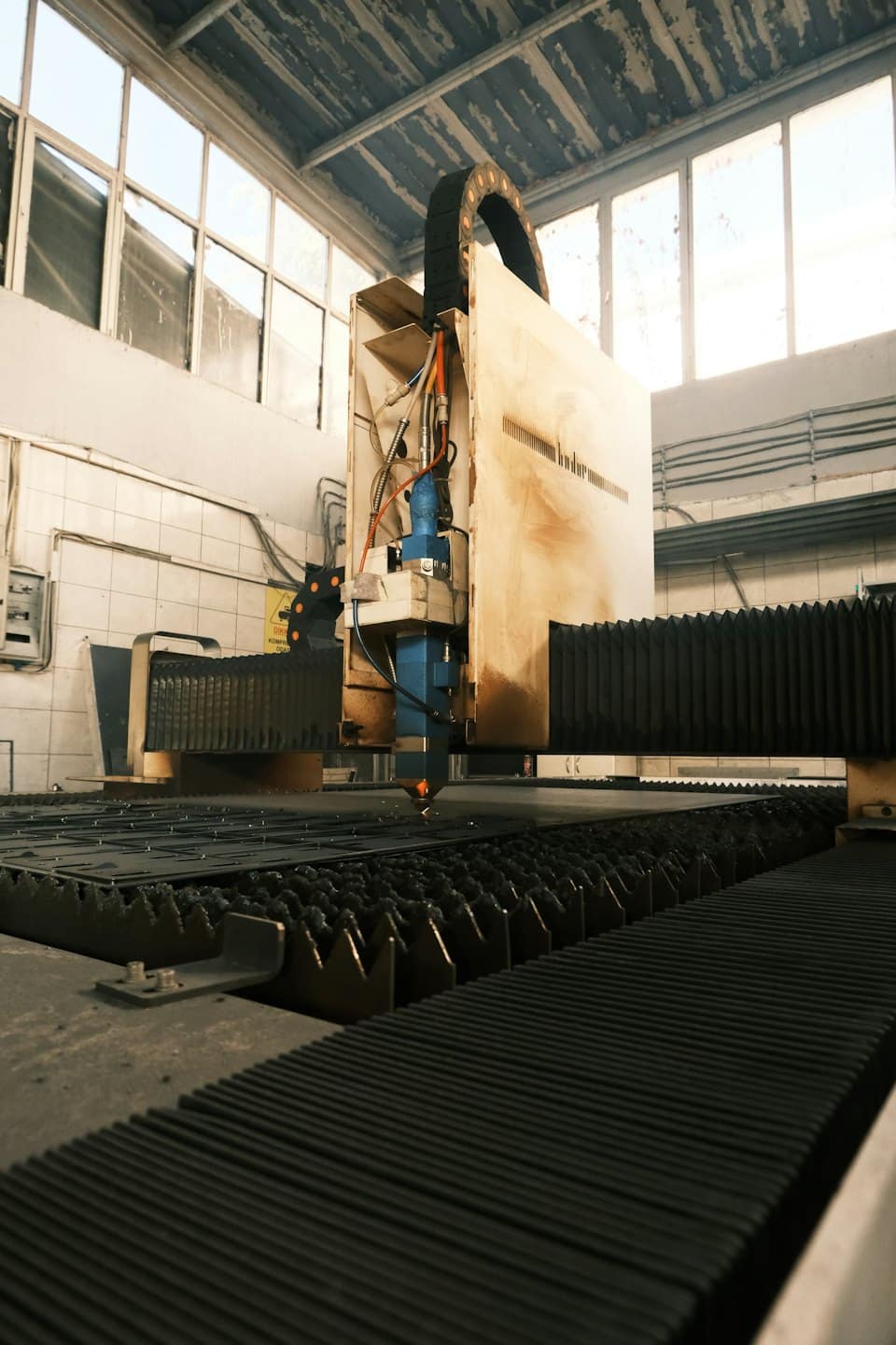 Taglio laser industriale su metallo con luce arancione brillante.