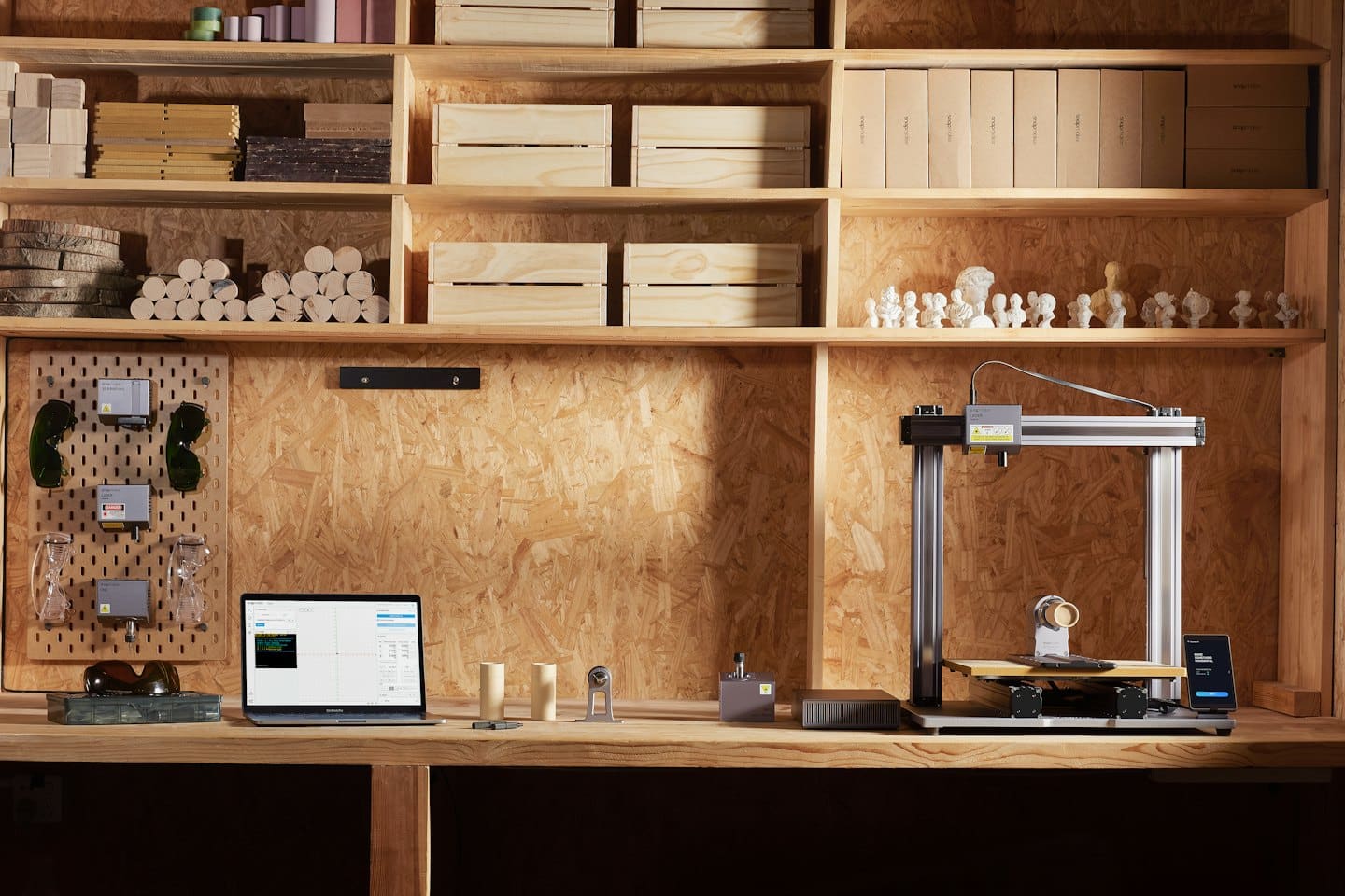 Inciditrice laser e stampante 3D su un banco da lavoro con laptop.