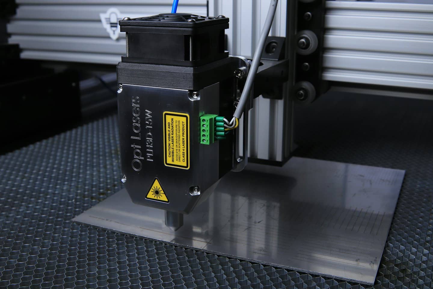 Incisore laser che traccia linee su una superficie metallica spazzolata.